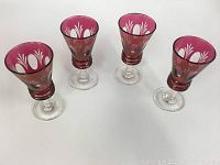 Four cranberry glasses arranged to show color, shape, and overall set condition.