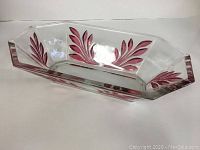 Front view of rectangular cranberry glass dish showing cranberry leaf pattern on clear glass.