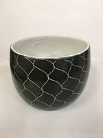 Front view of round ceramic dish showing black exterior with white wave pattern.