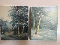 Two unframed oil paintings side by side showing winter forest scenes with snow on trees and ground.