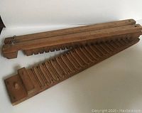 Top view of two wooden mold halves, showing the carved slots shaped for cigars with pin holes and locking pegs at one end.