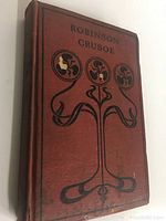 Front cover of the book showing the title 'Robinson Crusoe' with black floral decoration on reddish-brown background.