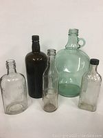 Lot of five vintage glass bottles arranged in two rows on white background.