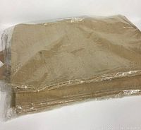 Ten beige placemats shown in folded stacks, wrapped in clear plastic.