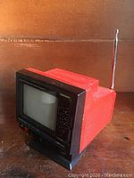 Side and top view of the vintage Pulser portable mini TV showing red casing, telescoping antenna, and overall design.