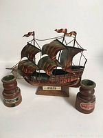 Photo of metal model ship of the Pinta, multiple sails and flags, mounted on base with name plaque