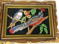 Photo capturing the entire framed needlepoint depicting two birds on branches, showing frame details and needlepoint colors.
