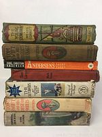 Seven vintage children's books stacked horizontally showing colorful spines with titles such as The Young Snowman, Andersen's Fairy Tales, Tom Swift series, and The Castaways.