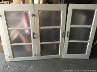 Set of three vintage wooden windows with textured glass arranged side-by-side, showing full frames and paint condition.