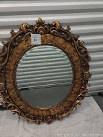 Full view of the oval tortoise framed decorative mirror showing ornate gold trim and tortoise shell pattern frame with mirror glass.
