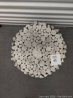 Top view showing cut ends of cylindrical wooden pieces on the table surface, whitewashed finish