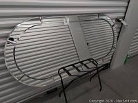 Full length oval decorative mirror resting against a storage wall, showing minor damage near the bottom edge.