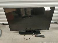 Front view of Samsung 32-inch flat screen TV on stand with remote control placed in front.