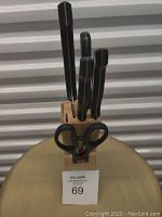 Front view of knife block containing various knives and kitchen scissors.