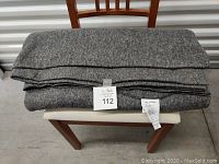 Gray fleece blanket folded on chair showing general condition and size.