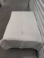 Full view of a white cotton towel folded and placed on a table, showing its size and texture.