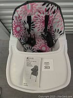 Front view of ZOE high chair showing padded floral seat cover with black harness straps and removable white tray attached.