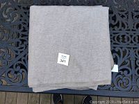 Top view of folded beige fleece blanket with inventory tag 341 on patterned outdoor table