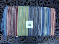 Folded blanket showing colorful striped pattern and advertisement label number 347.