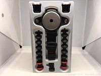 Top view of the GorillaPod Rig Upgrader components in white molded tray packaging including flexible arms, rig mount plate, strap mount buckle, and accessory mounts.