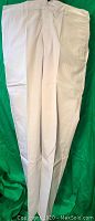 Front view of white G501 style pants laid flat on green background, showing crease and pocket details.