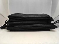 Stack of 10 black folded microfibre towels showing thickness and uniformity