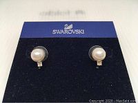 Pair of Swarovski earrings displayed on branded backing card, showing crystal pearl and small faceted crystal detail.