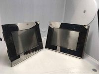 Front view showing two rectangular stainless steel photo frames with reflective surfaces, black backing, and visible wear spots on corners.