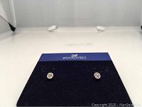 Pair of Swarovski crystal stud pierced earrings displayed in black Swarovski holder showing clear crystals in bezel setting.