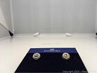 Front view of Swarovski Angelic rhodium plated crystal pierced earrings on original black display card with Swarovski branding.