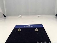Front view of the pair of Swarovski crystal solitaire stud earrings mounted on a Swarovski branded card.