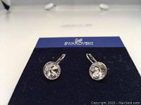 Pair of clear round Swarovski Bella mini earrings with white rhodium plating displayed on blue Swarovski card.