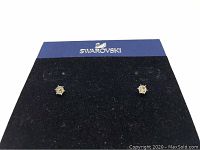 Close-up front view of Swarovski piercing stud earrings mounted on branded display card.