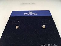 Front view of Swarovski stud earrings on a black Swarovski branded display card showing the earrings secured in place.
