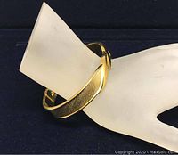 Photo of gold-tone Monet bracelet displayed on a mannequin hand showing the textured band and clip design.