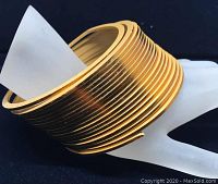 Close-up of retractable slinky style brass colored bracelet showing coiled metal bands and wear marks.