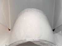 Front view of a clear plexiglass face shield curved and attached to headgear.