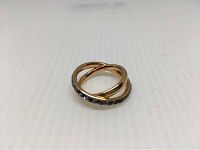 Rose gold plated ring with black crystals visible on the curved band, slight scuffing noted on the metal.