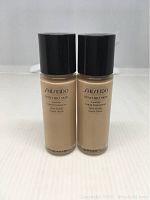 Front view of two Shiseido Synchro Skin Lasting Liquid Foundation bottles in shade Golden 2 with black caps on a white background.