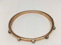 Rose gold plated bangle bracelet with Swarovski crystals, showing side profile and clasp area, size marked M.