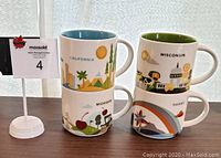 Front side view of four Starbucks You Are Here mugs featuring California, Michigan, Wisconsin, and Hawaii states with their respective themed illustrations and colored interiors.