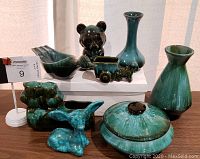 Full lot view showing all eight pieces, various animal shaped pottery, vases and lidded bowl in green glaze with some brown details