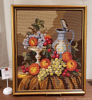 Front view of the vintage cross stitch artwork showing a detailed fruit bowl, grapes, cherries, peaches, and a decorative pitcher framed in gold.