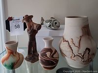 View of four pottery items including three Nemadji vases and two figurines, one fish and one trumpet player. Items are displayed on a flat surface.