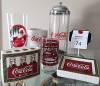 Photo of all Coca Cola collection items grouped together: two Christmas themed glasses, ceramic mug, straw dispenser, toothbrush holder, soap dish