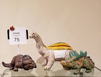 Three ceramic dinosaur figurines displayed together, showing scale and colors