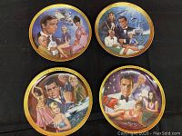 Four James Bond themed commemorative collector's plates arranged together on black cloth showing detailed artwork and gold rims.