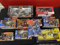 Overview of ten boxed die-cast motorcycle models including Harley-Davidson, Mikey's Bike, and Discovery Channel Rider Bikes, placed on a black surface.
