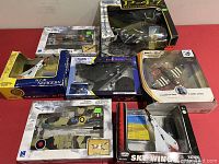 All airplane model kits arranged in a group on red surface showing worn boxes and various designs and brands.