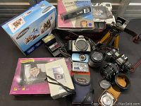 Overview of entire lot showing cameras, lenses, flash units, packaging, tripod, cases